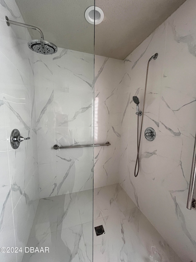 bathroom with a textured ceiling and tiled shower