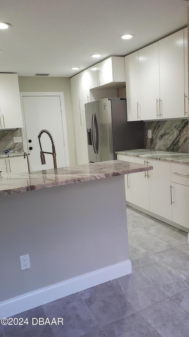 kitchen with light stone countertops, white cabinetry, sink, and backsplash