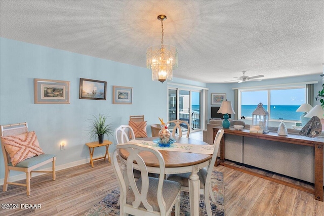 dining space featuring a water view, a textured ceiling, and light hardwood / wood-style floors
