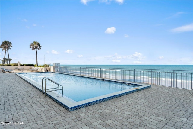 view of swimming pool with a patio area and a water view