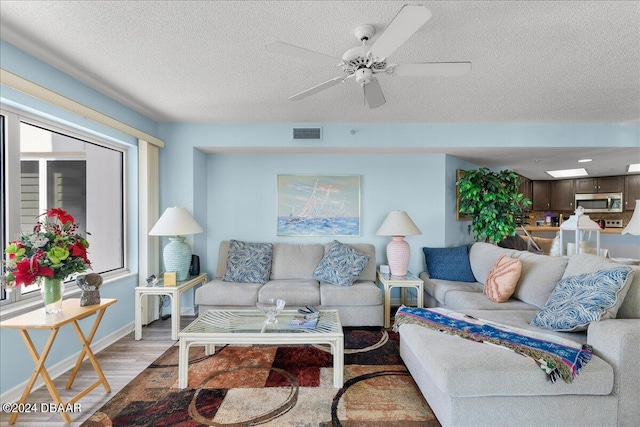 living room with ceiling fan, wood-type flooring, and a textured ceiling
