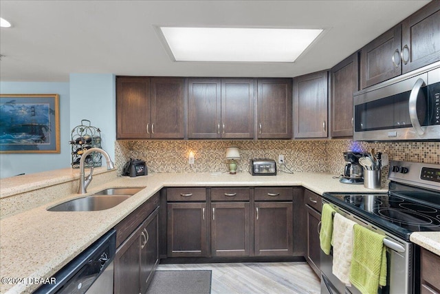 kitchen featuring stainless steel appliances, dark brown cabinetry, sink, backsplash, and light wood-type flooring