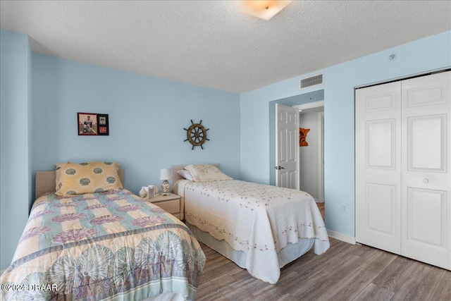 bedroom featuring a closet, wood-type flooring, and a textured ceiling