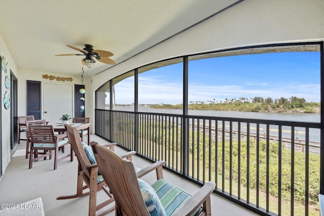 sunroom featuring ceiling fan and a water view