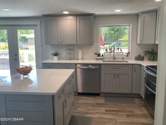 kitchen featuring sink, gray cabinets, appliances with stainless steel finishes, backsplash, and dark hardwood / wood-style floors