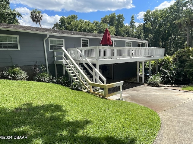 rear view of property featuring a carport, a yard, and a deck