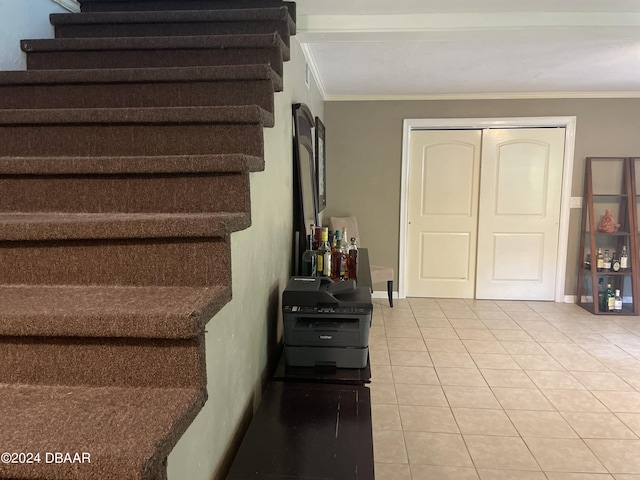 stairway with crown molding and tile patterned floors