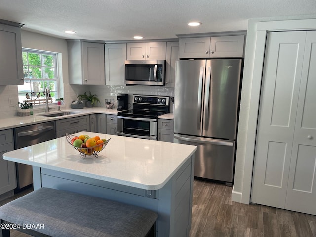 kitchen featuring sink, a breakfast bar, stainless steel appliances, dark hardwood / wood-style flooring, and decorative backsplash