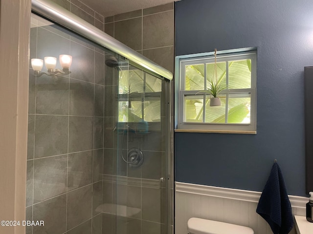 bathroom featuring toilet and a shower with shower door