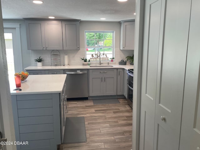 kitchen featuring gray cabinets, tasteful backsplash, sink, stainless steel appliances, and dark wood-type flooring