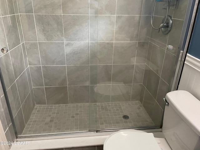 bathroom with toilet and a shower with shower door