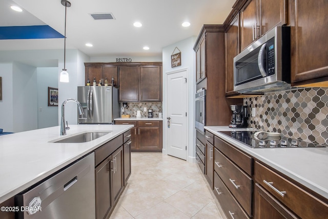 kitchen featuring hanging light fixtures, stainless steel appliances, decorative backsplash, dark brown cabinets, and sink