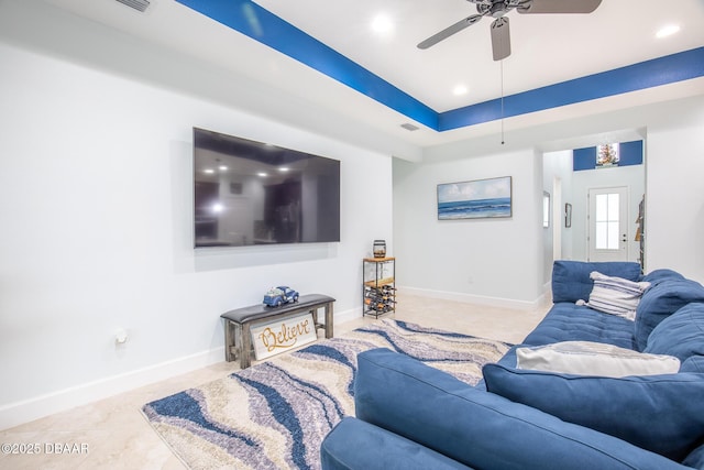 living room with a raised ceiling, light tile patterned flooring, and ceiling fan