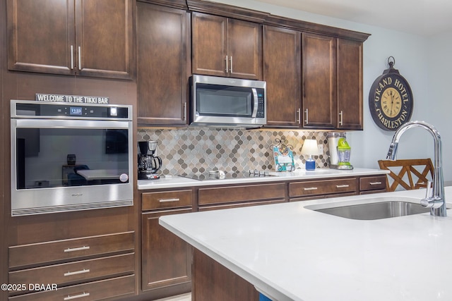 kitchen featuring appliances with stainless steel finishes, tasteful backsplash, dark brown cabinets, and sink