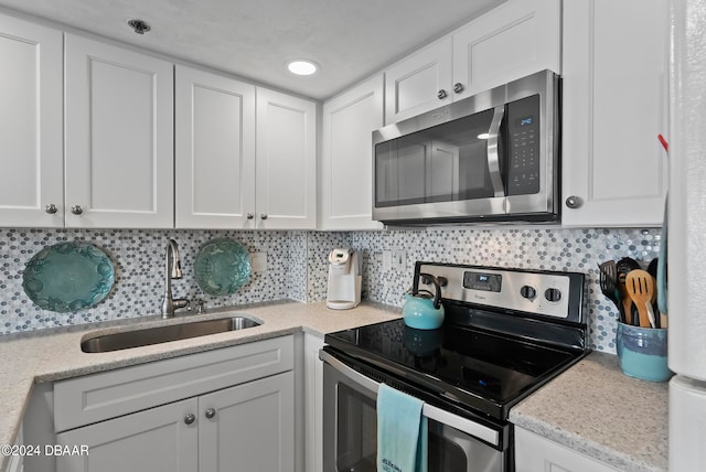 kitchen with tasteful backsplash, white cabinetry, sink, and stainless steel appliances