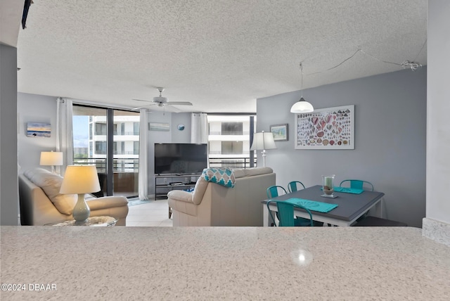 living room with expansive windows, a textured ceiling, light tile patterned floors, and ceiling fan