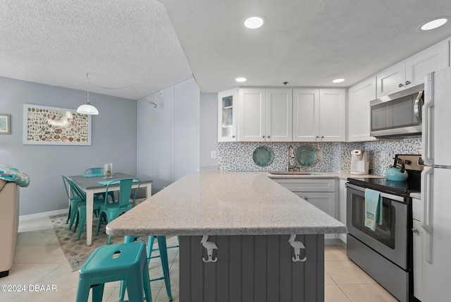 kitchen featuring white cabinetry, appliances with stainless steel finishes, hanging light fixtures, sink, and kitchen peninsula