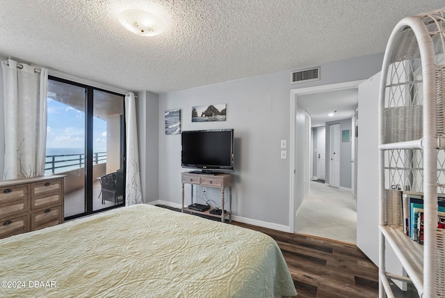 bedroom with a textured ceiling, dark hardwood / wood-style floors, and access to exterior