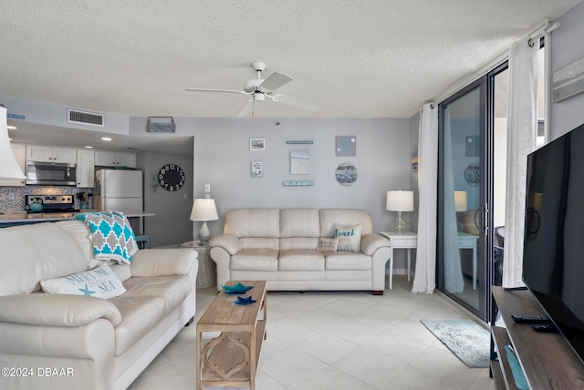 living room featuring a textured ceiling, light tile patterned floors, and ceiling fan