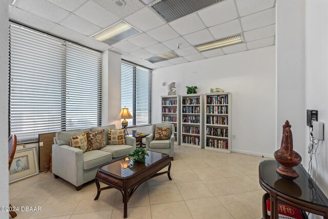 living room with a paneled ceiling and light tile patterned floors