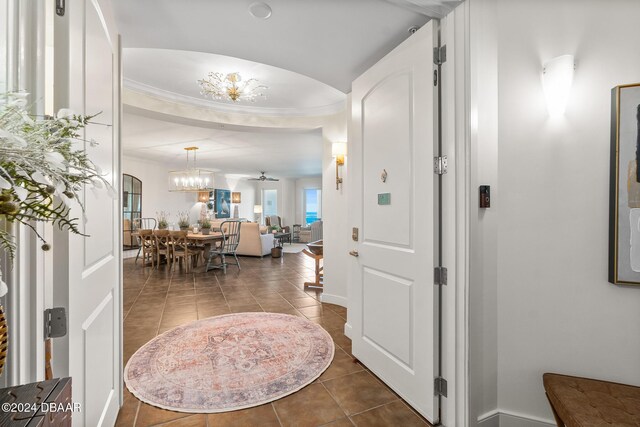 tiled foyer with ceiling fan with notable chandelier and ornamental molding