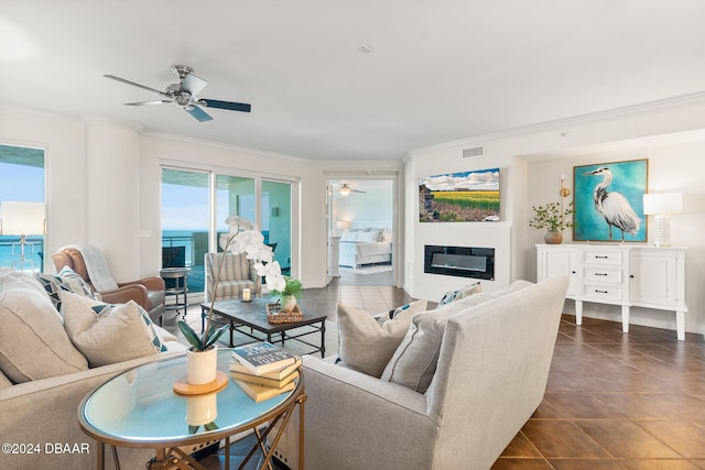 tiled living room with a water view, ceiling fan, and ornamental molding