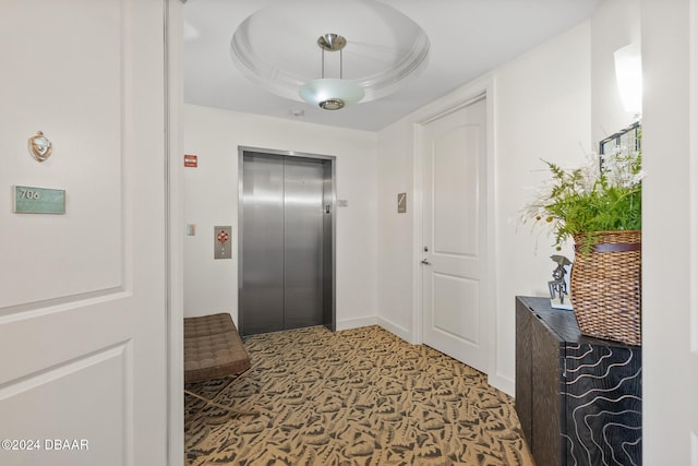 hall featuring a raised ceiling and elevator