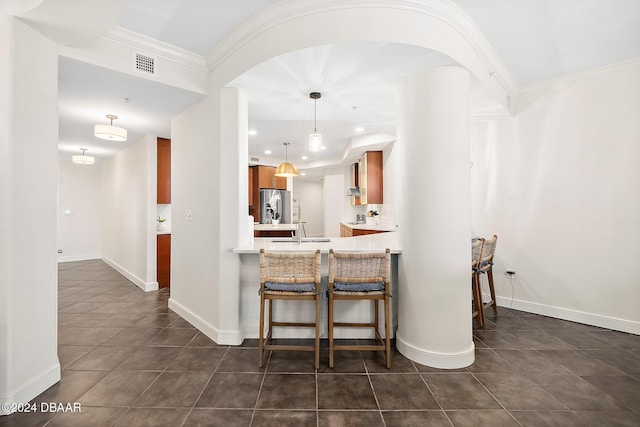 kitchen featuring pendant lighting, sink, stainless steel fridge, ornamental molding, and kitchen peninsula