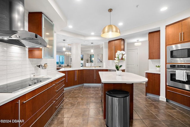 kitchen featuring decorative light fixtures, a kitchen island, wall chimney range hood, and stainless steel appliances