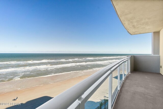 balcony with a water view and a view of the beach