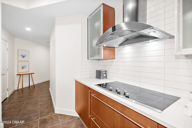 kitchen featuring black electric stovetop, dark tile patterned floors, wall chimney range hood, and backsplash