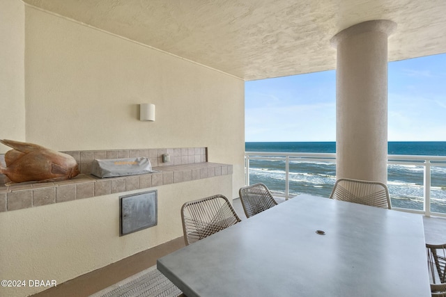 dining area with a healthy amount of sunlight, a water view, and a view of the beach