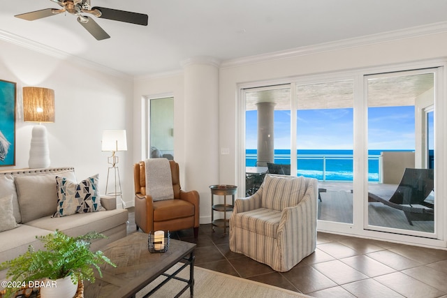 living room with ceiling fan, dark tile patterned floors, a water view, and crown molding