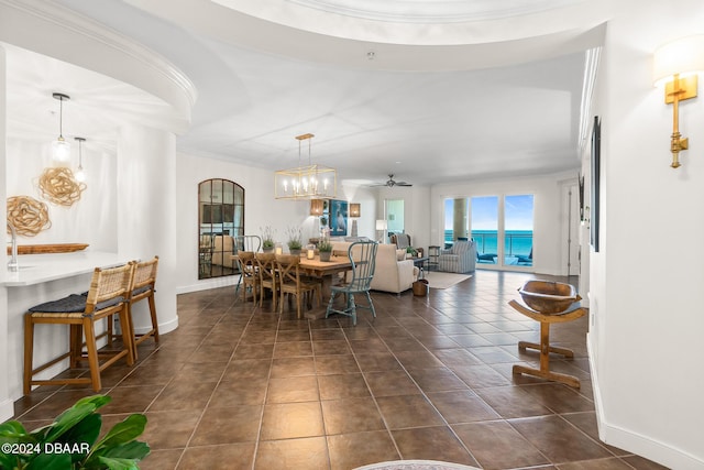 tiled dining room featuring ceiling fan, a water view, and ornamental molding