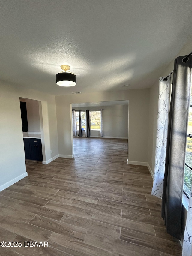 empty room with baseboards, dark wood finished floors, and a textured ceiling