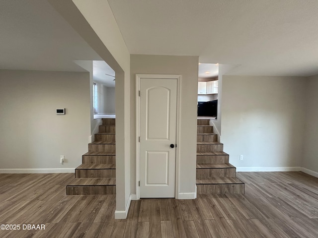 stairway featuring baseboards and wood finished floors