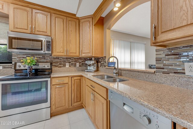 916 Ashmeade Ct, Port Orange, FL 32127 - kitchen with stainless steel appliances, decorative backsplash, arched walkways, light stone countertops, and light tile patterned flooring
