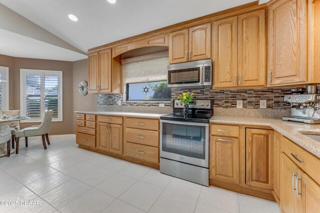 916 Ashmeade Ct, Port Orange, FL 32127 - kitchen with stainless steel appliances, vaulted ceiling, backsplash, light tile patterned floors, and recessed lighting