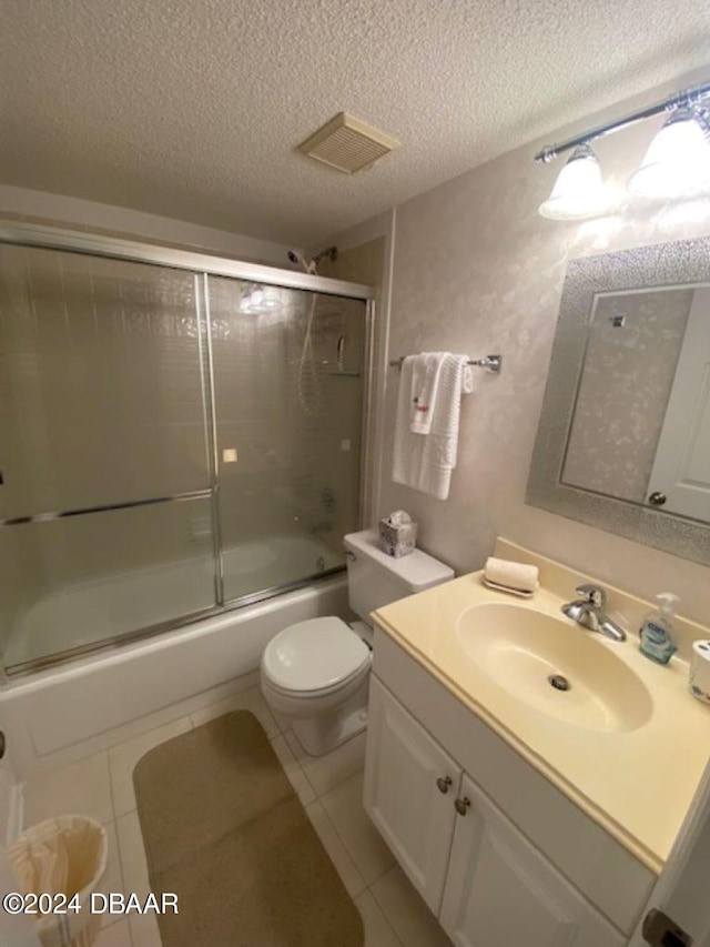 full bathroom featuring toilet, bath / shower combo with glass door, a textured ceiling, and tile patterned flooring