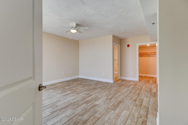 empty room with a textured ceiling, light hardwood / wood-style flooring, and ceiling fan