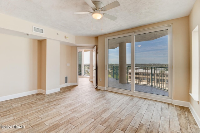 spare room featuring a textured ceiling, light wood-type flooring, and ceiling fan