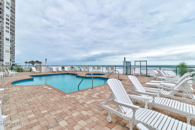 view of pool featuring a patio and a water view