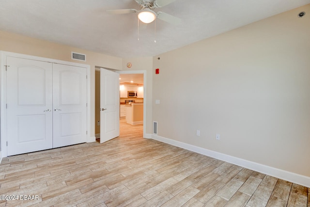 unfurnished bedroom with ceiling fan, a closet, and light wood-type flooring