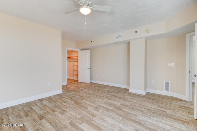 spare room featuring a textured ceiling, light hardwood / wood-style flooring, and ceiling fan