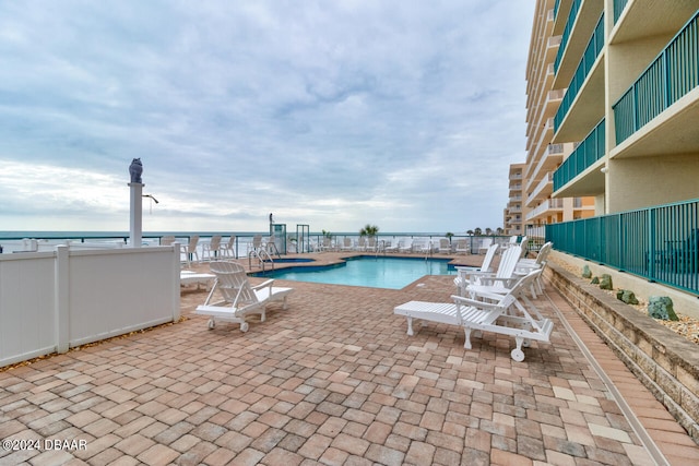 view of swimming pool featuring a water view and a patio area