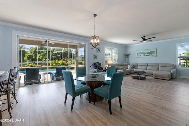 dining area featuring light wood-type flooring, ceiling fan with notable chandelier, and crown molding