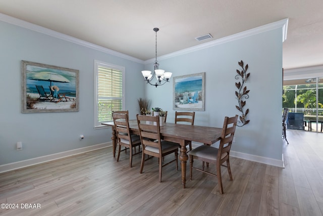 dining room featuring ornamental molding, light wood-type flooring, and a notable chandelier