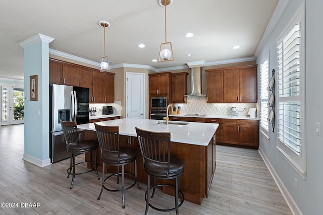 kitchen featuring stainless steel appliances, wall chimney exhaust hood, sink, and light wood-type flooring