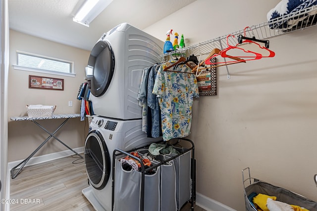 laundry area featuring stacked washer / dryer and light hardwood / wood-style flooring