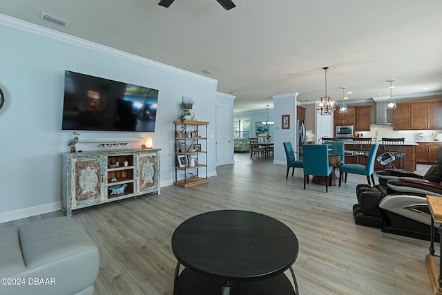 living room featuring ceiling fan with notable chandelier, light hardwood / wood-style flooring, and crown molding